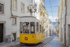 Elétrico amarelo tradicional a subir uma rua estreita e íngreme em Lisboa 