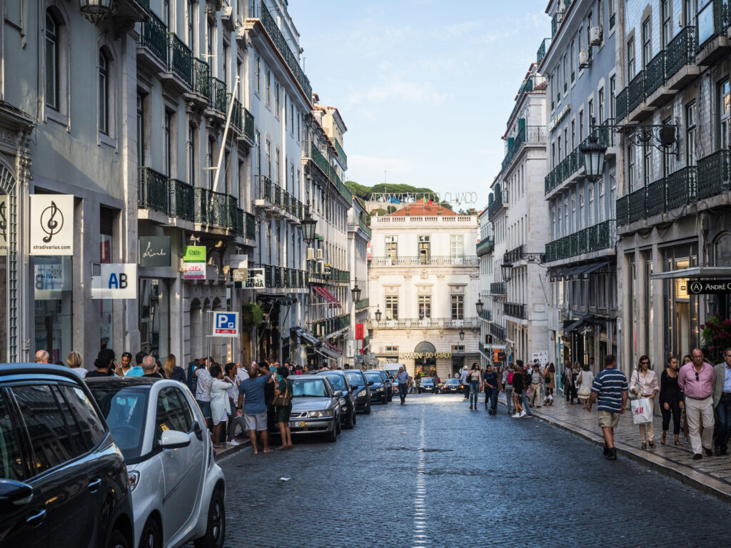 Rua comercial no Chiado, em Lisboa, com fachadas tradicionais e movimento pedonal